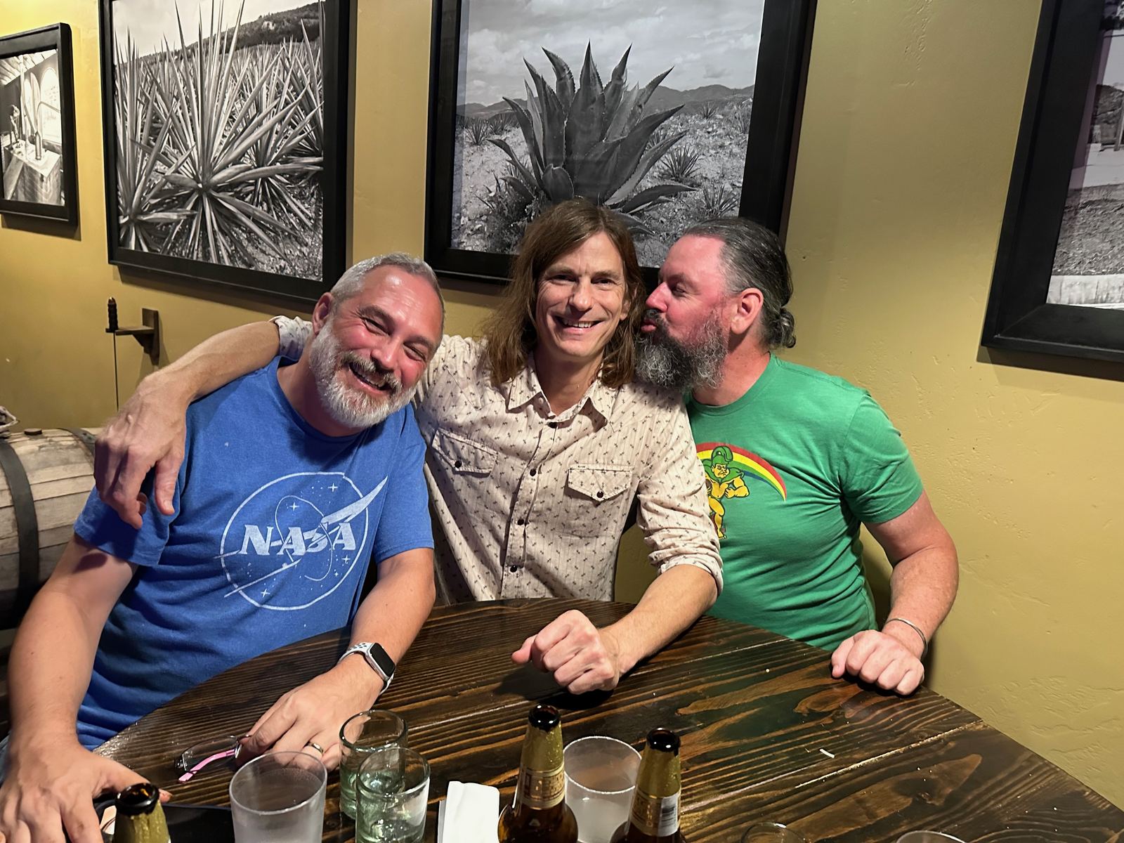 Alan and two friends at a table with agave photography on the wall